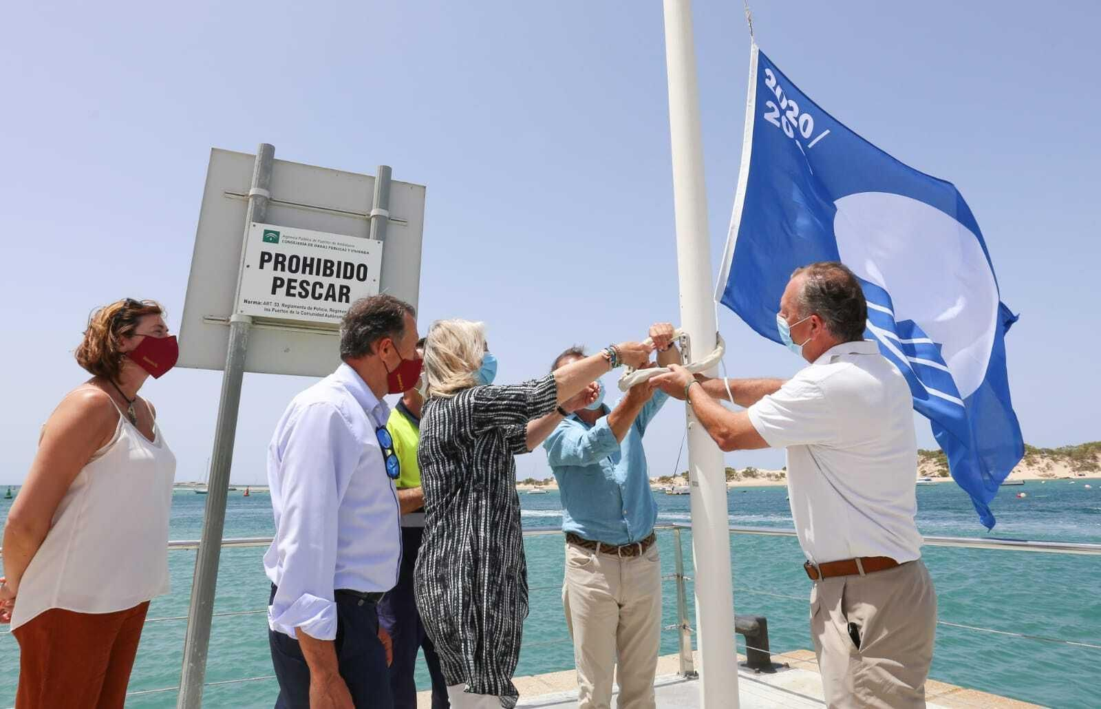 Momento del izado de la Bandera Azul en el puerto de Sancti Petri por parte de los responsables de la Junta y el Consistorio.