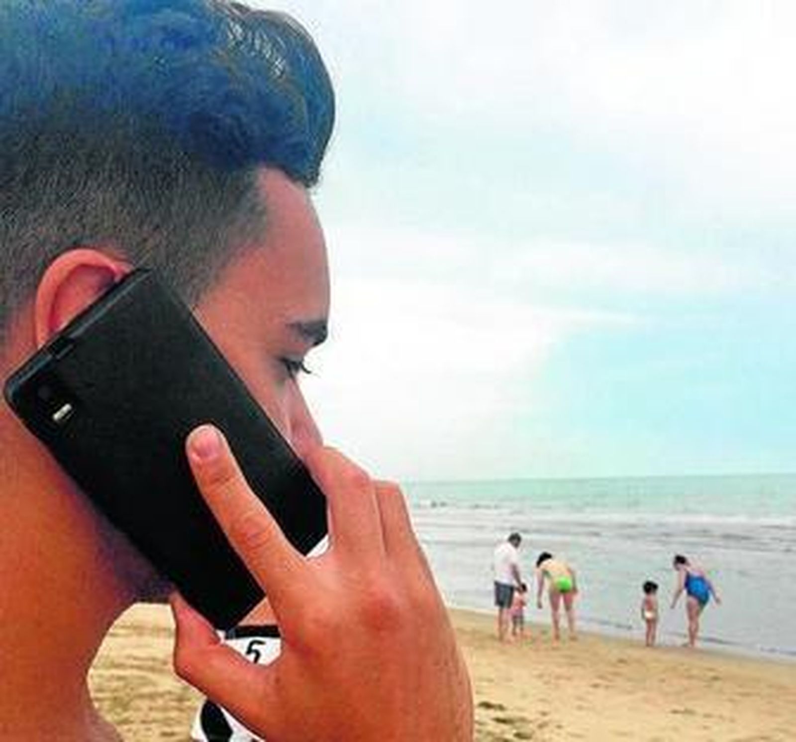 Joven habla por su teléfono móvil en la costa onubense.