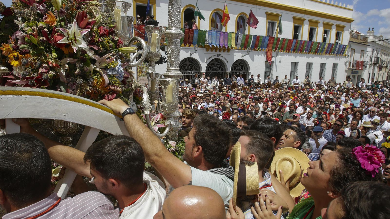 Brazos de peregrinos sostienen la carreta de Coria tras subir al porche de la parroquia manriqueña.