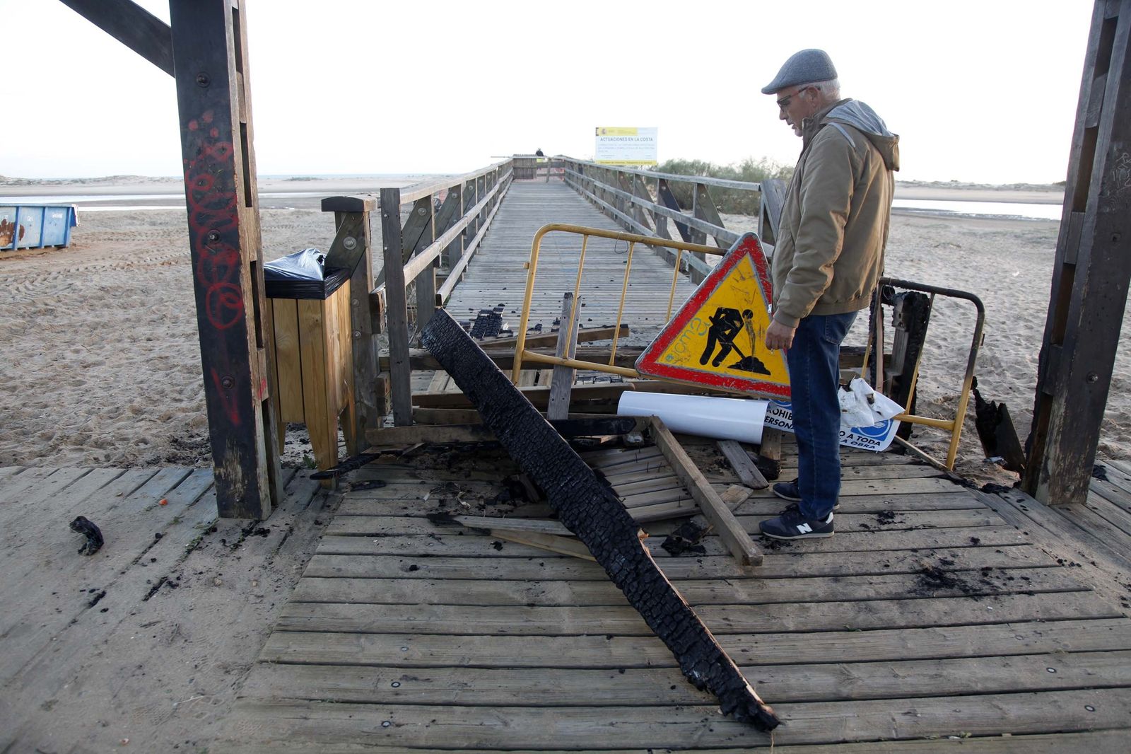 Un hombre mira los desperfectos causados por el fuego a la entrada del puente de La Gola.