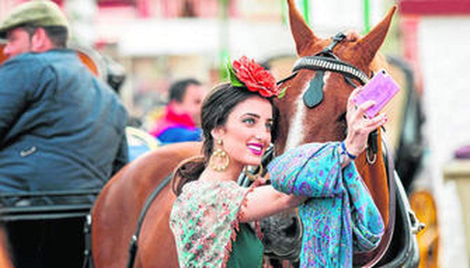 Una joven vestida de flamenca se hace una fotografía con un caballo el pasado sábado en la Feria.