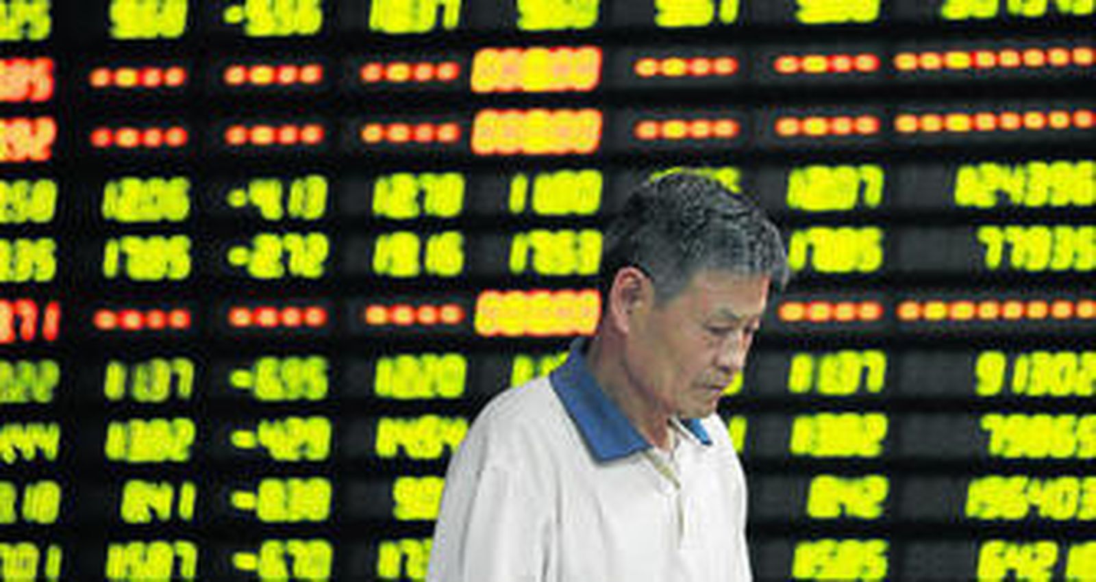 Un inversor pasa junto a una pantalla que muestra la evolución de los valores en Bolsa.
