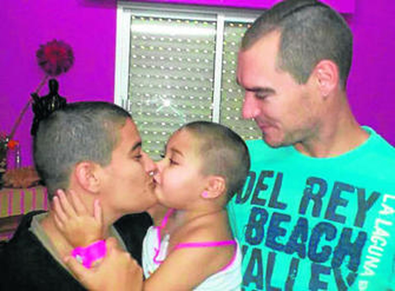 Nora junto a sus padres, todos con el pelo corto.