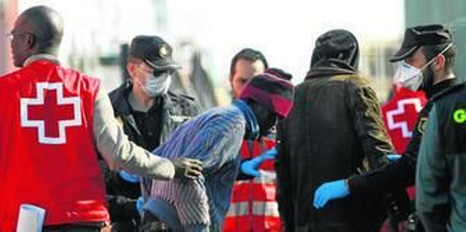 Los inmigrantes de la ya llamada patera de la muerte, ayudados por voluntarios de Cruz Roja Almería y por la Policía Nacional a su llegada al puerto de Almería.