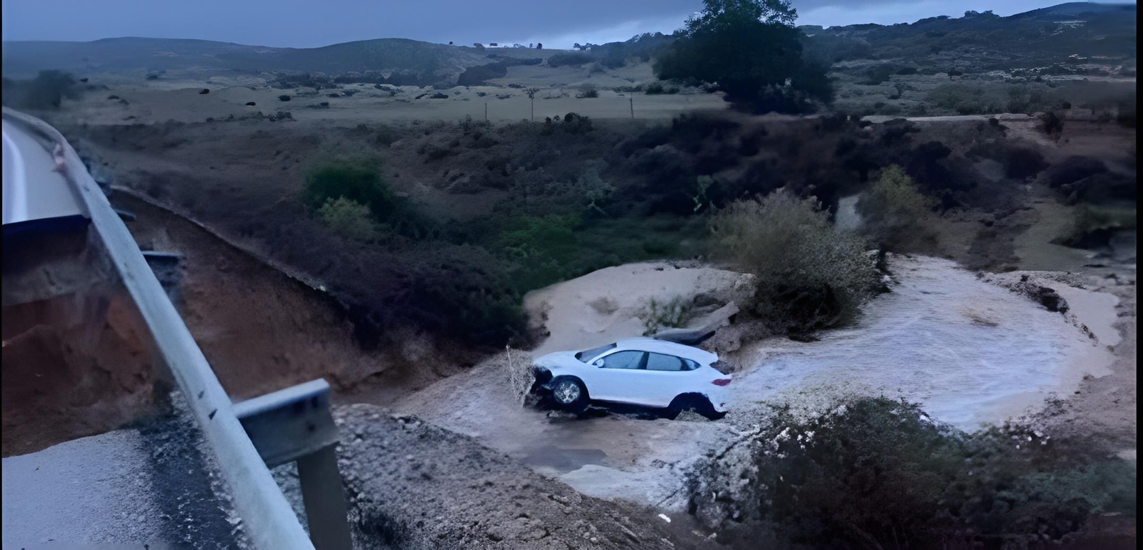 El vehículo arrastrado por un arroyo tras el derrumbe del puente en la A-476 a su paso por El Castillo de las Guardas.