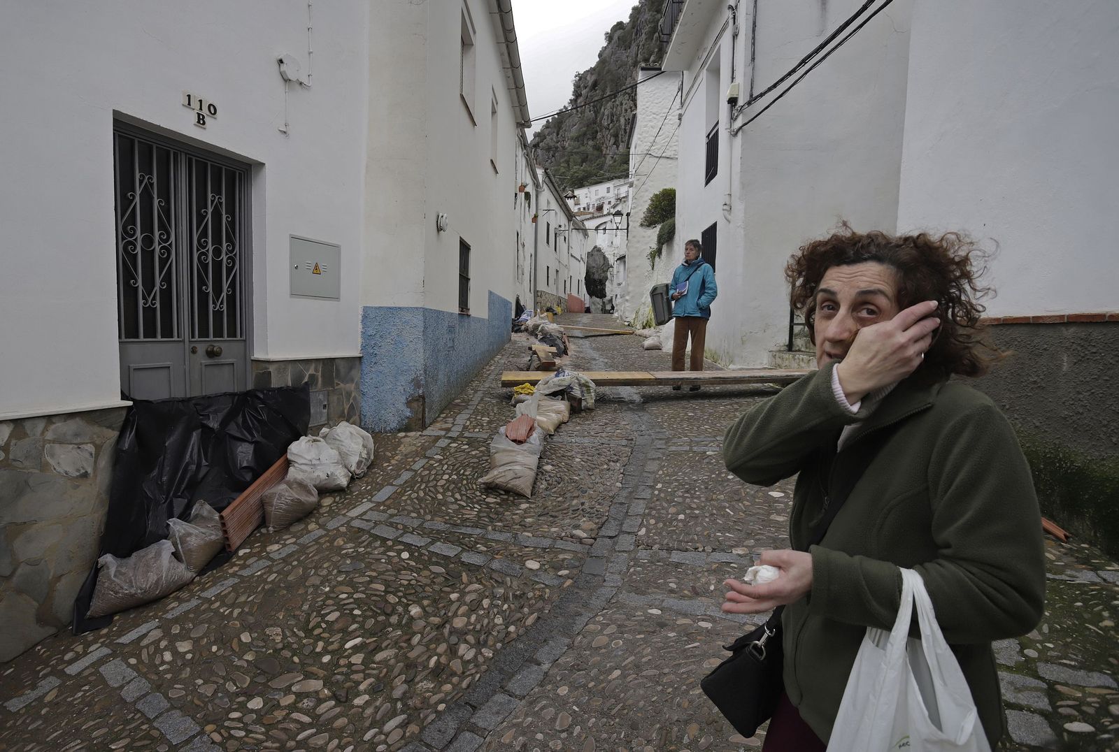 Desde el 7 de febrero se autorizó que el agua corriera en superficie por varias zonas del municipio para aliviar la presión de la red con el fin de evitar el colpaso de viviendas y tuberías. Una vecina muestra el estado de la calle La Torre tras pasar 3 días incomunicada en su casa a pesar de los diques y pasarelas habilitadas. para el curso del agua.