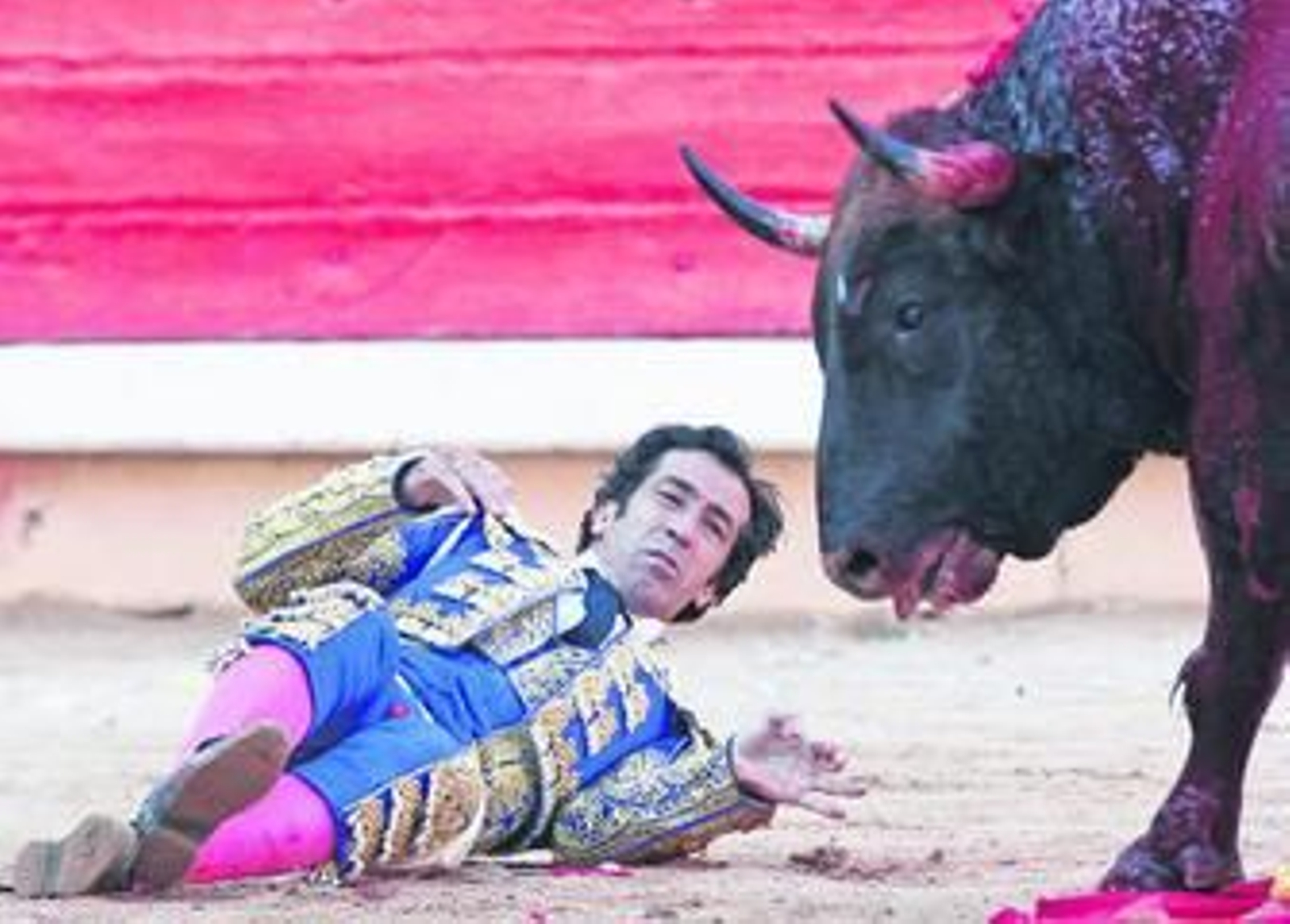 Juan Mora observa desde el suelo con gesto dolorido al toro que acaba de cornearle.
