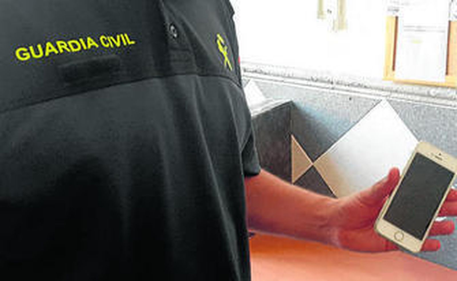 Un agente de la Guardia Civil con el terminal móvil sustraído y recuperado.