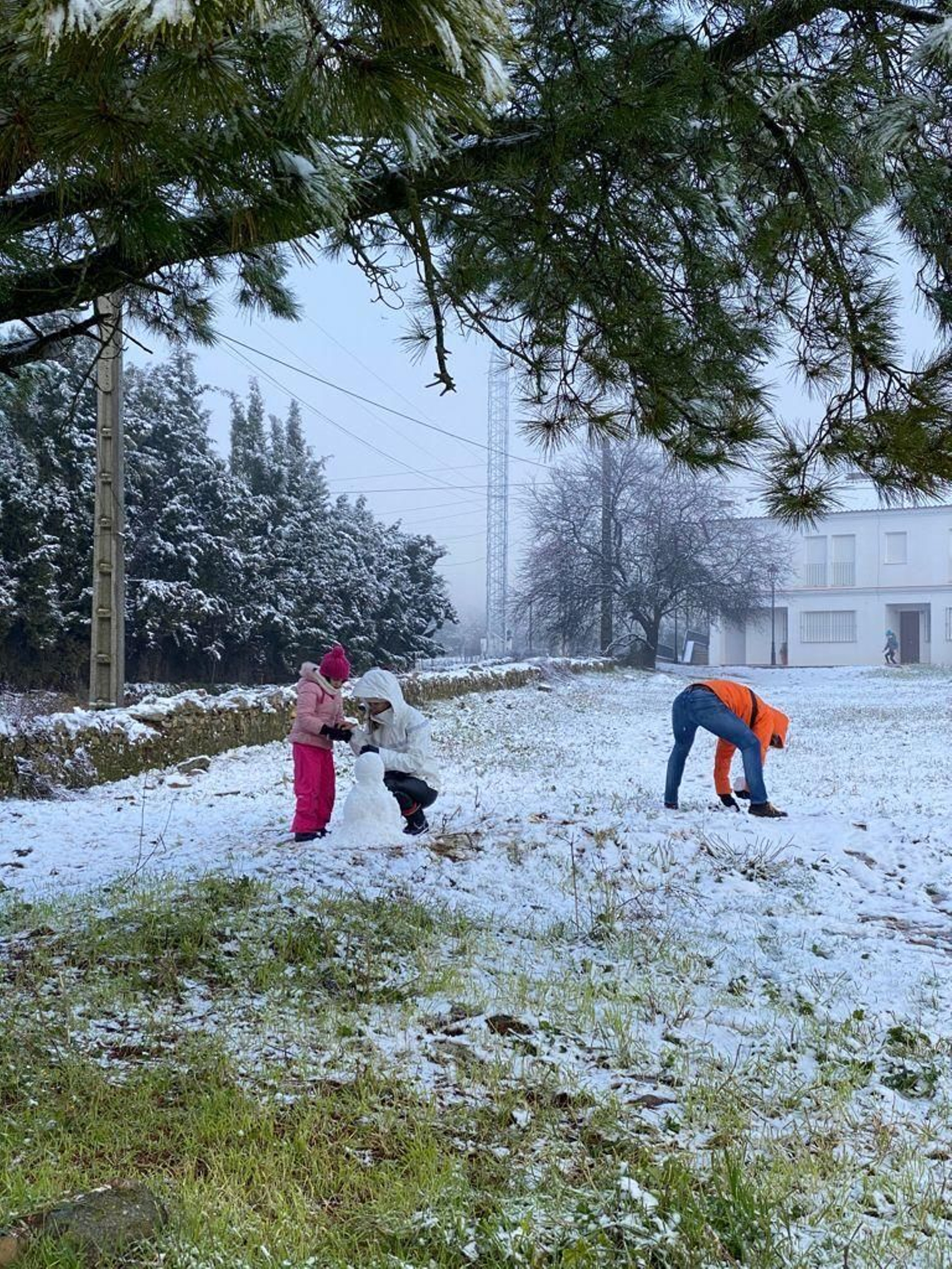Una familia haciendo un muñeco de nieve en la localidad de Alanís.