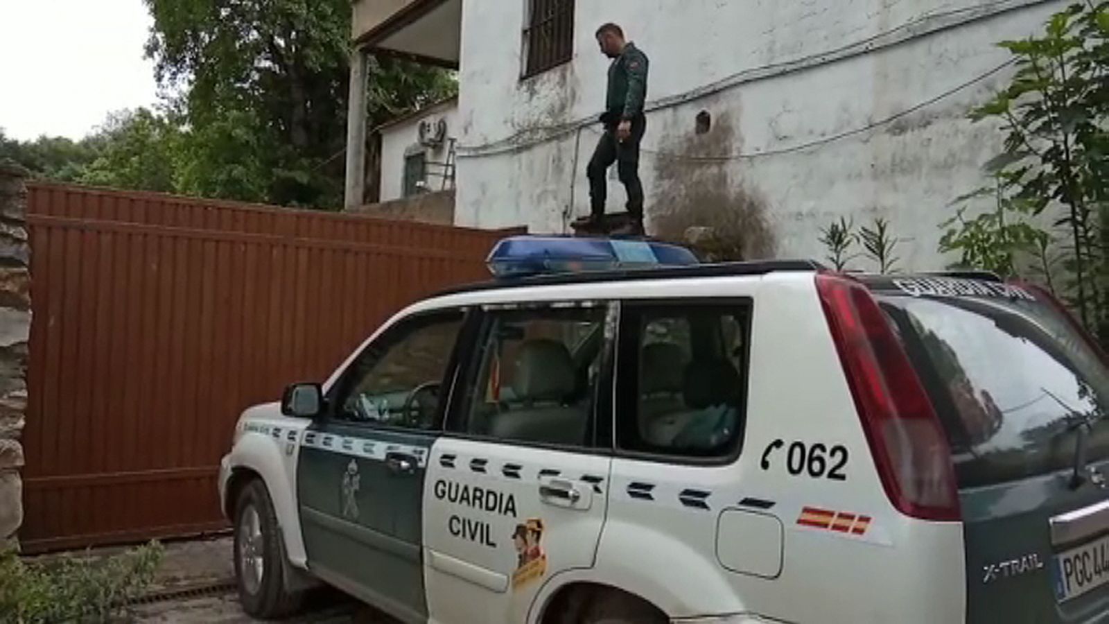 Uno de los guardias, encima del vallado de la casa.