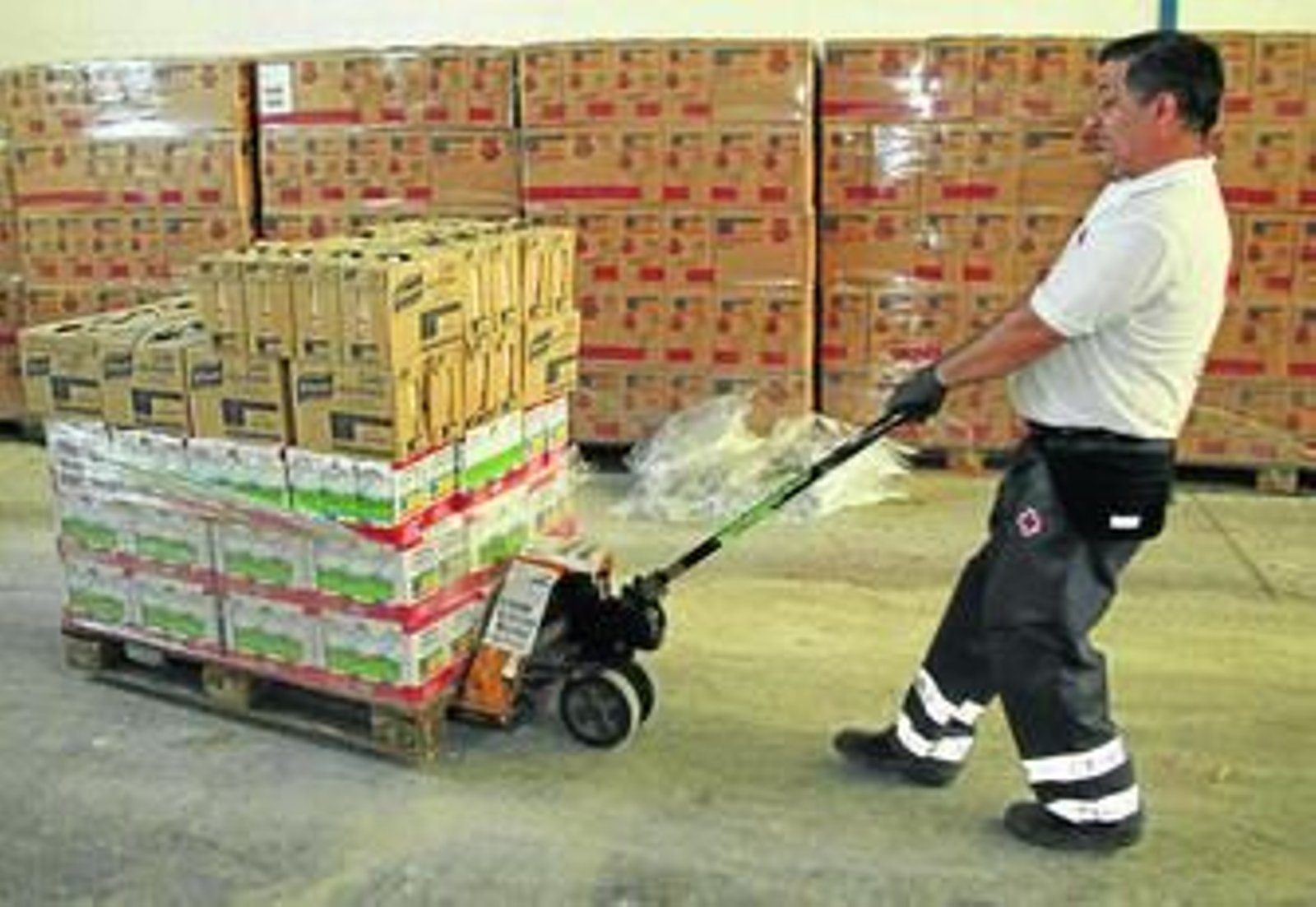 Un voluntario transporta alimentos en el almacén de la Cruz Roja.