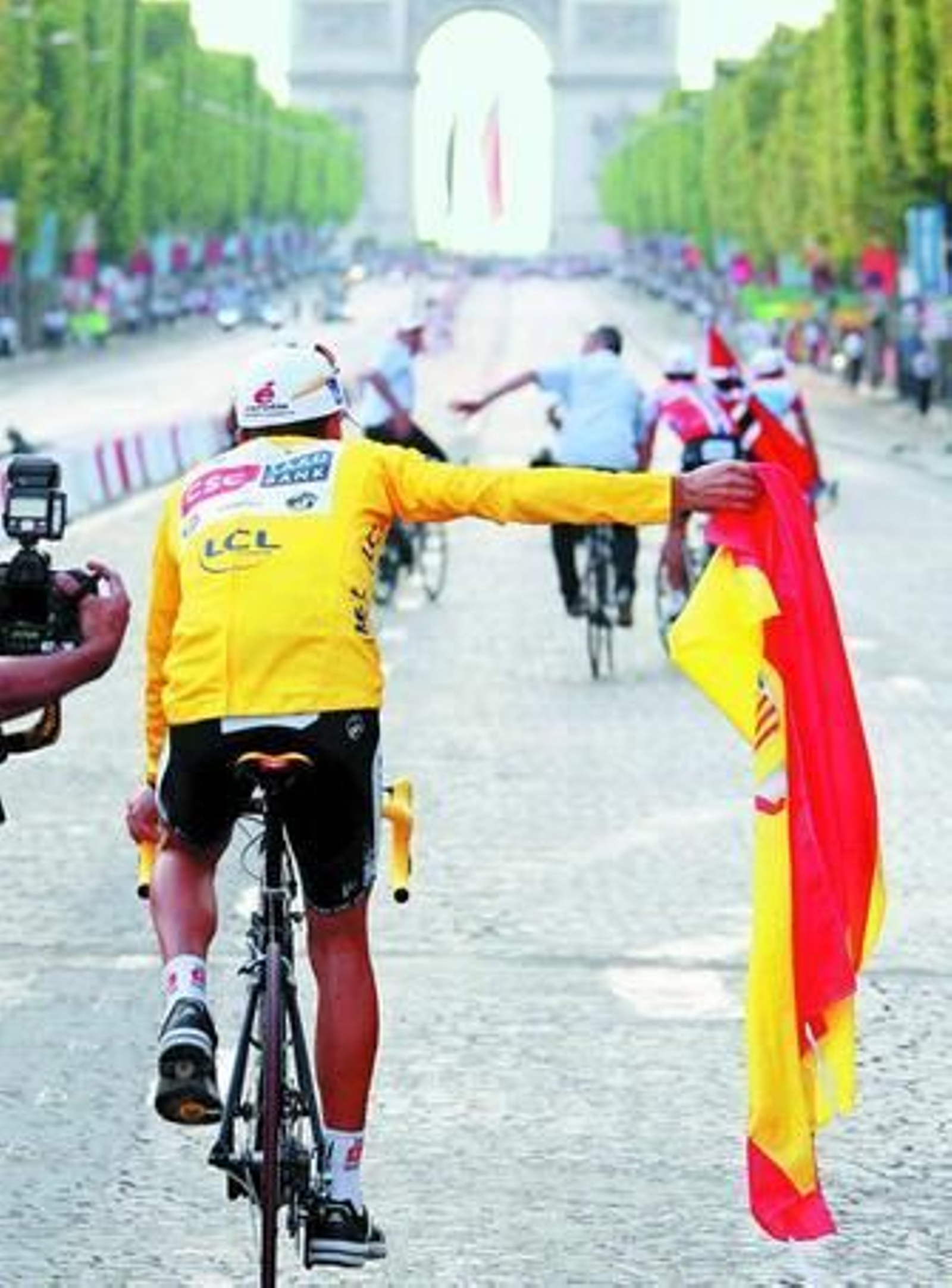 Carlos Sastre pasea la bandera de España, por tercer año consecutivo, por los campos Elíseos de París.