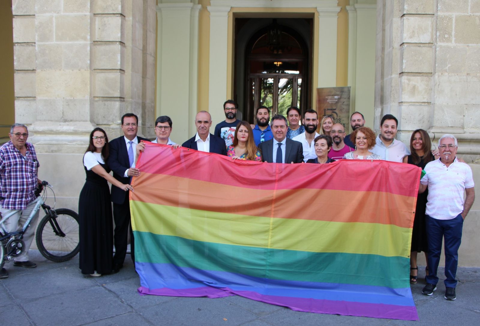 Representación municipal junto a la bandera del Orgullo Gay que lucirá en el Ayuntamiento de Sevilla.