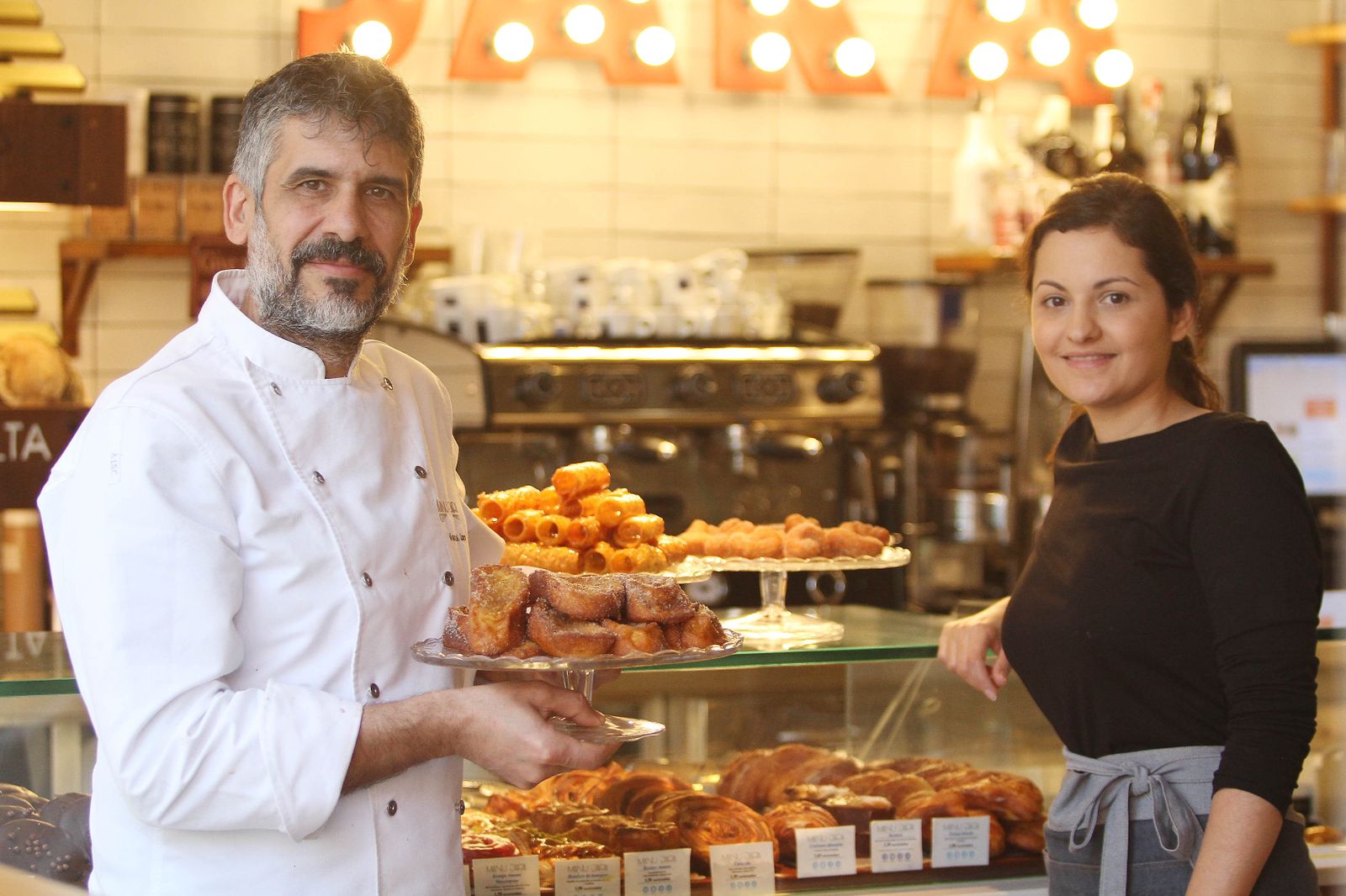 1. Manu Jara y Rosa Rodríguez están  al frente de este proyecto. 2. Ahora trabajan las torrijas y los pestiños. 3. Una joven con una bandeja de rosquillas.