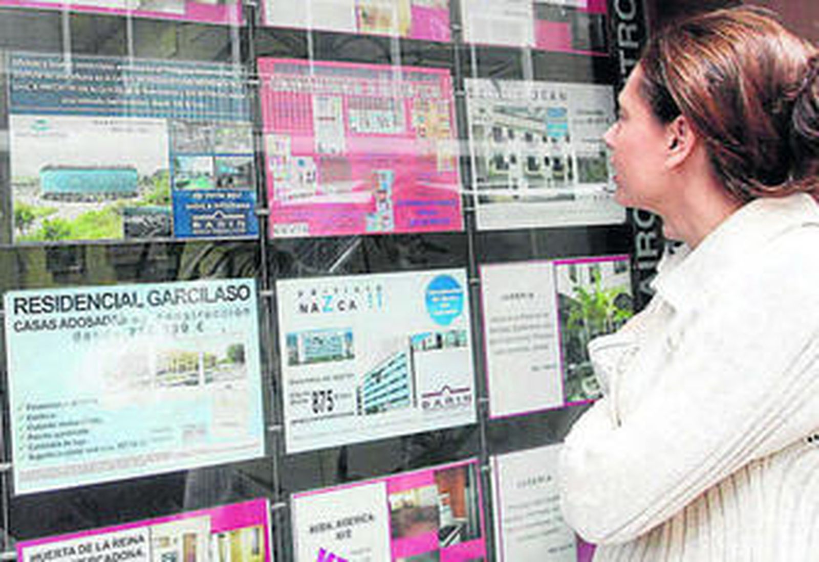 Una mujer mira las ofertas de viviendas en régimen de alquiler de una agencia inmobiliaria.