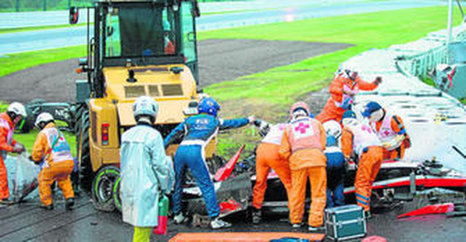 Los comisarios y médicos del circuito de Suzuka atienden a Bianchi tras estrellar su monoplaza contra la grúa que retiraba otro coche.