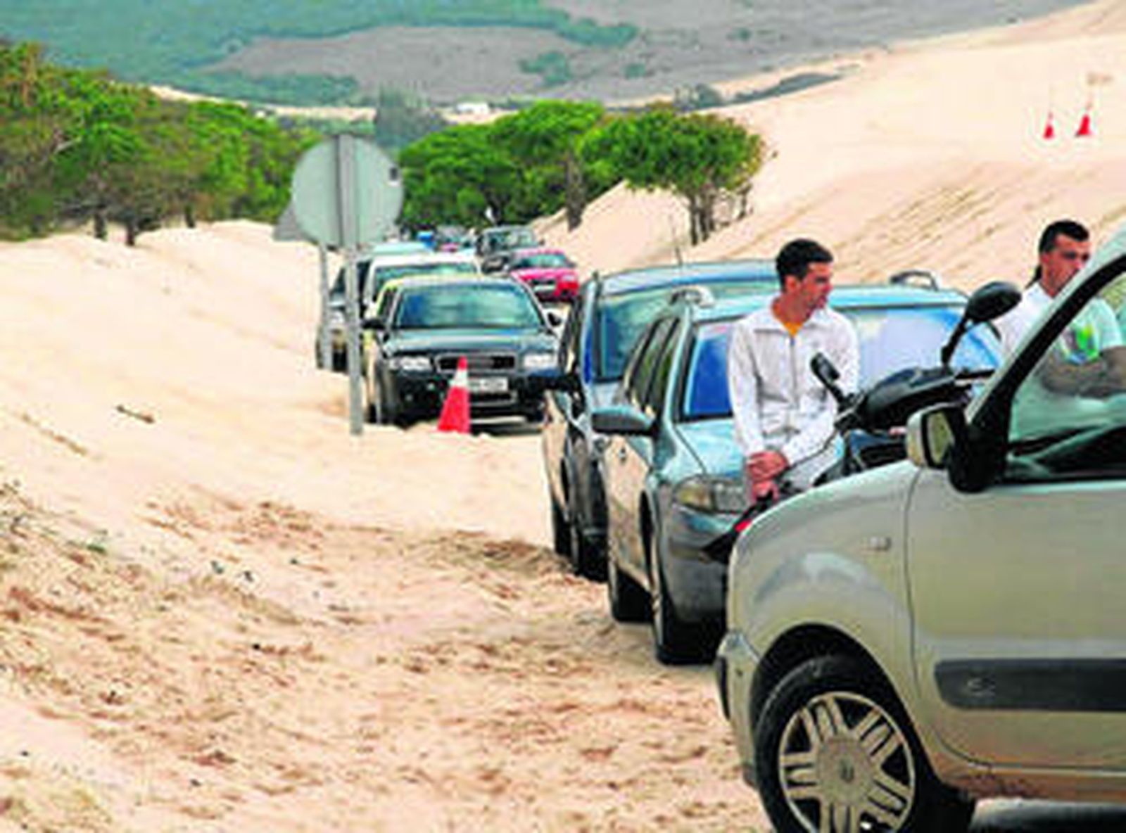 Imagen de archivo de dos vecinos junto a una caravana de coches, en una protesta reciente.