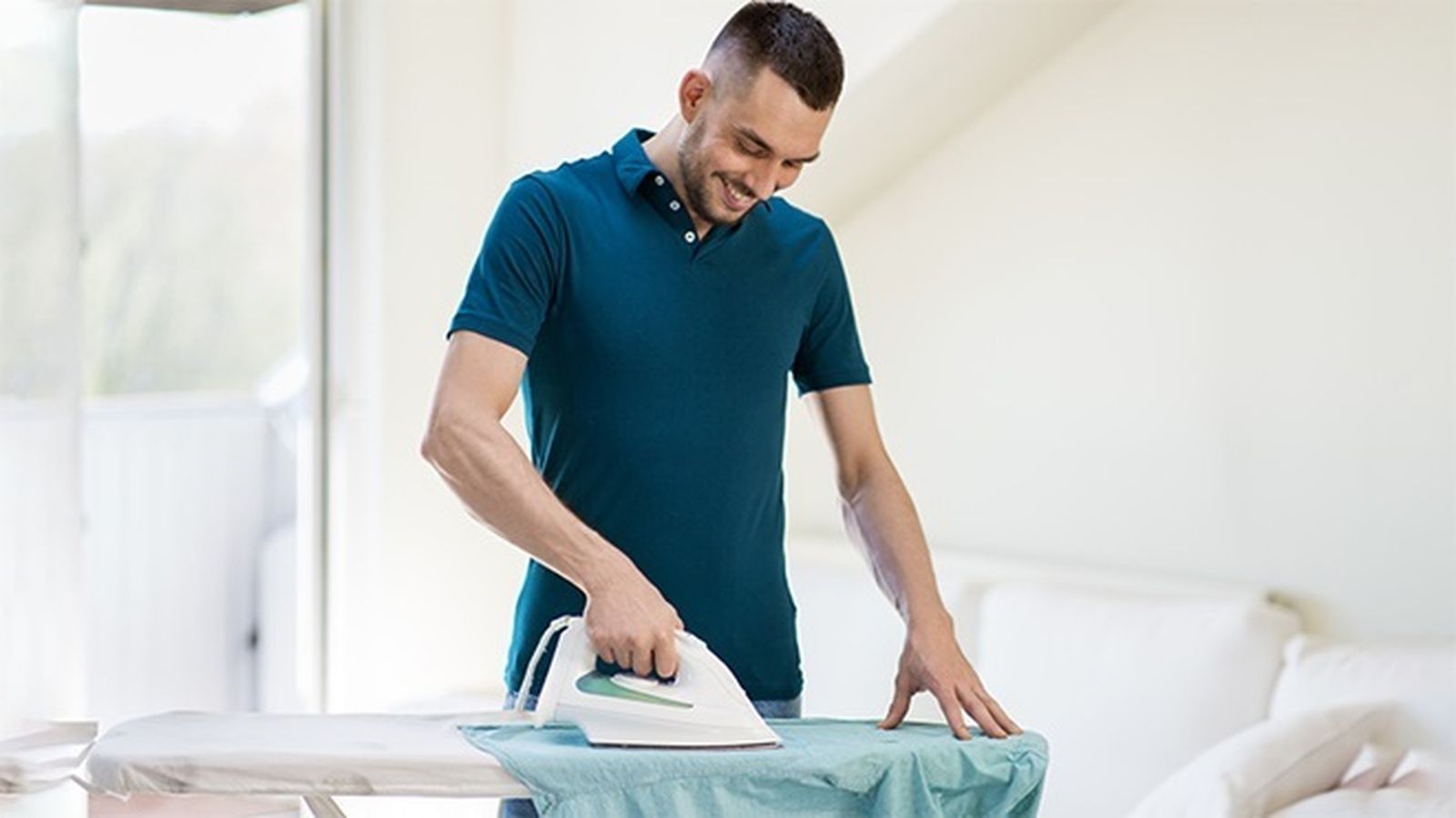 Un hombre plancha una camisa