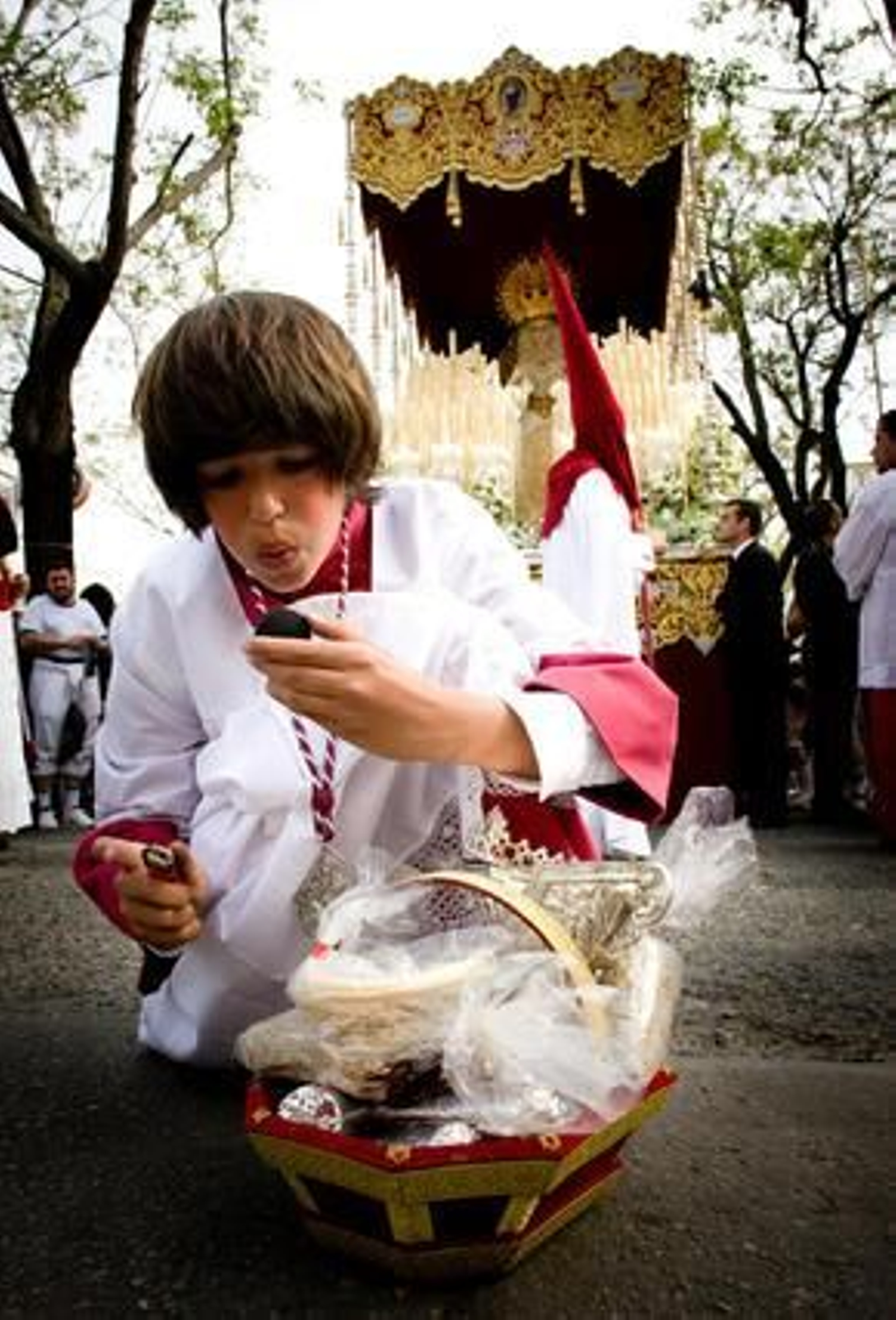El paso previo. Un monaguillo del paso de palio prepara una pastilla de carbón que posteriormente depositaría en el incensiario para así anunciar a los ciudadanos la llegada de María Santísima del Refugio.

Foto: Juan Carlos Toro