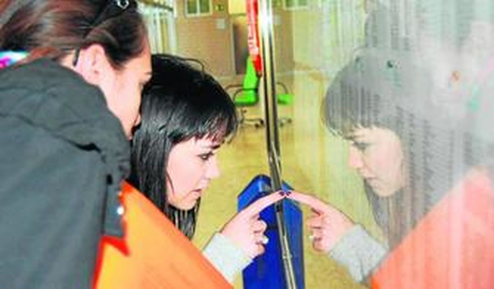 Dos estudiantes comprueban las listas de admitidos en el tablón del Centro de Lenguas.