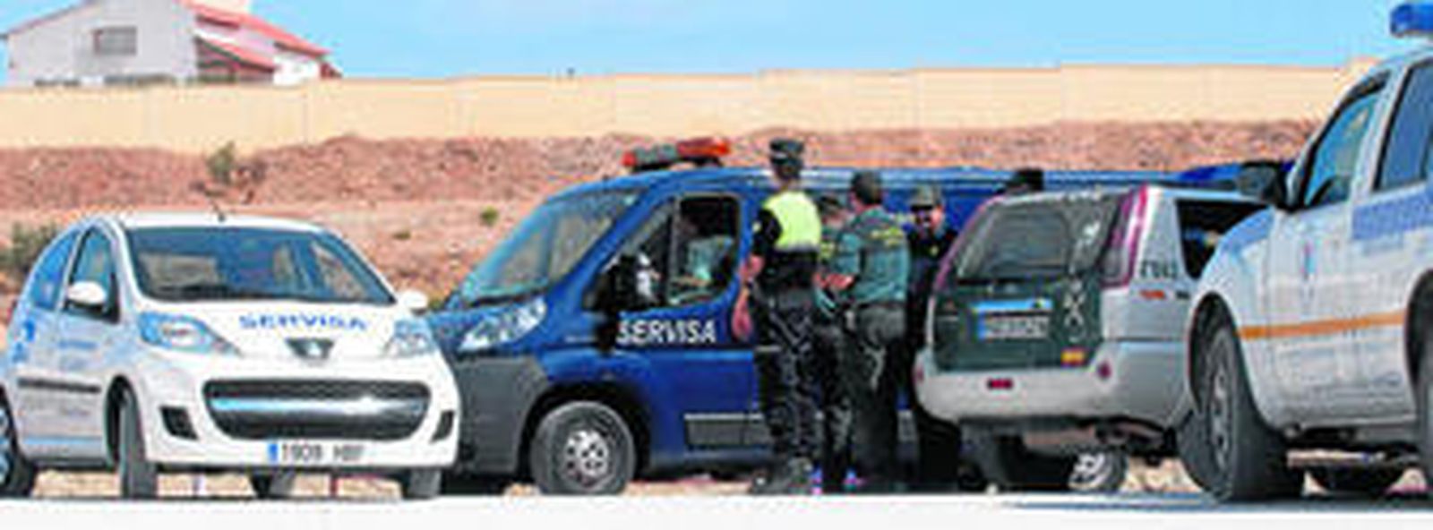 La Guardia Civil y la Policía Local, ayer, junto al furgón fúnebre en el campo de fútbol de Casariche.