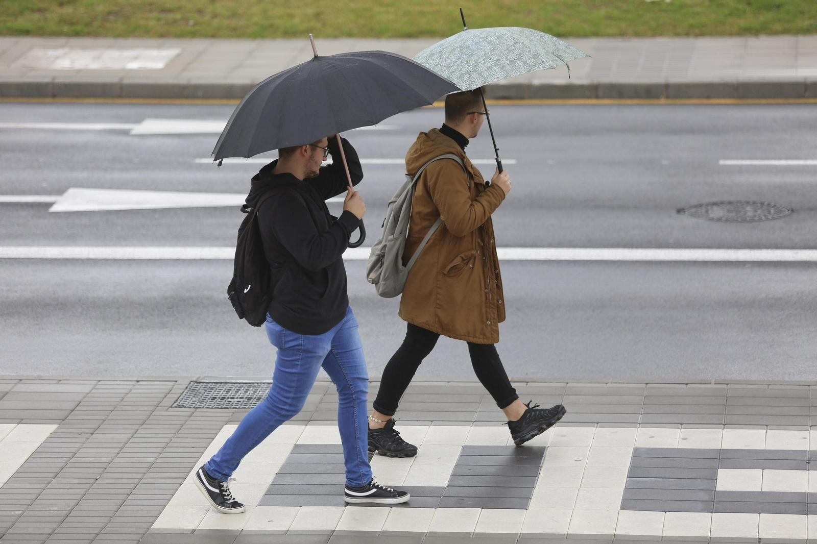 Dos jóvenes con paraguas en Málaga capital.