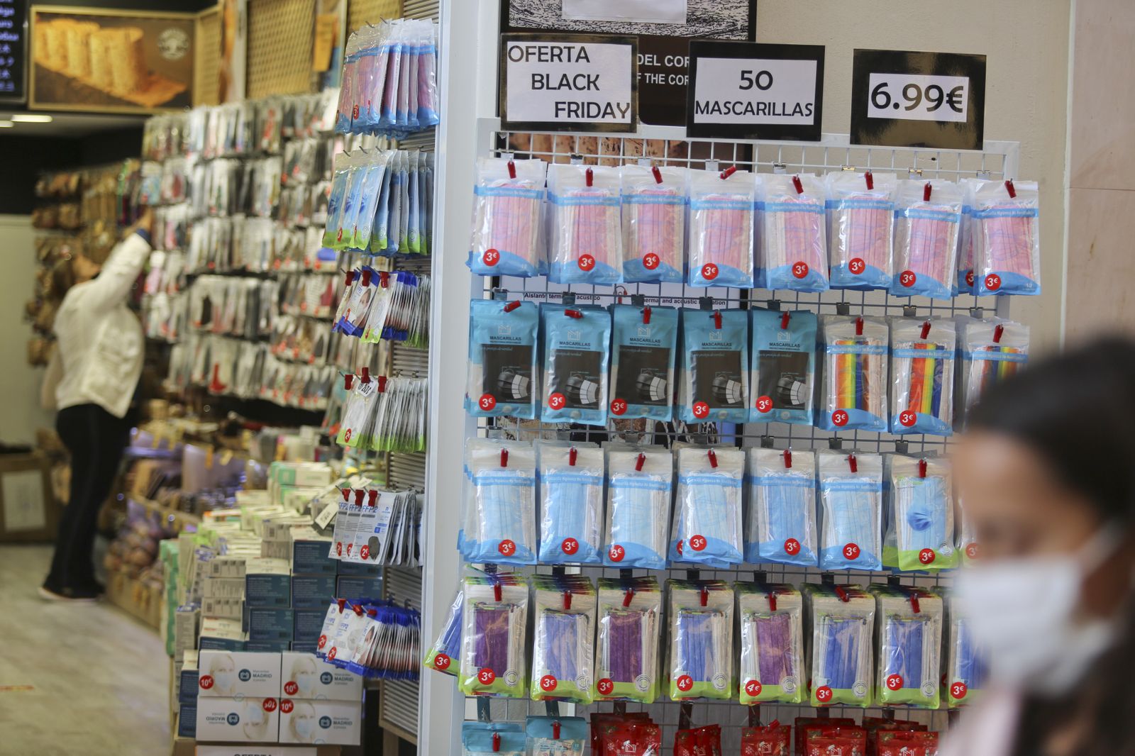 Una joven pasa junto a un negocio con mascarillas para protegerse del Covid.