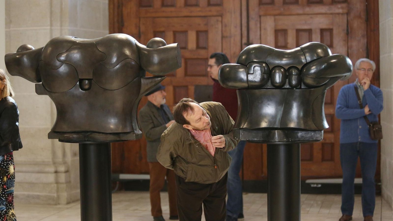 Un visitante observa de cerca uno de los bustos.