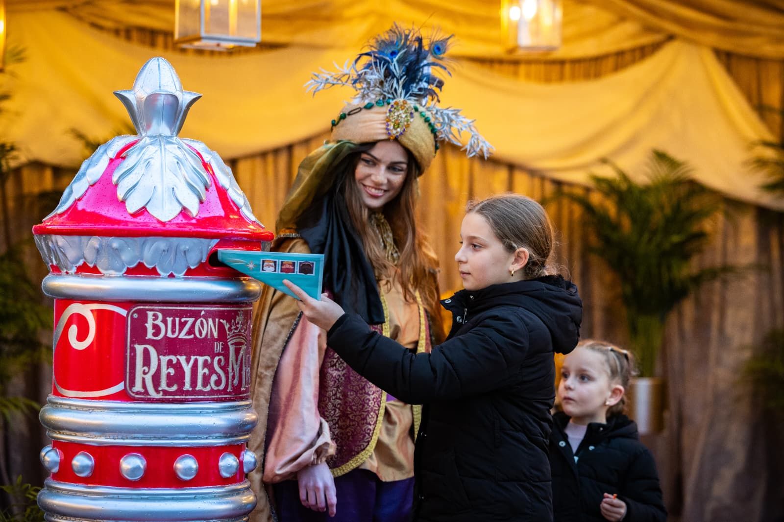 Unas niñas depositan sus cartas a los Reyes Magos en el buzón.