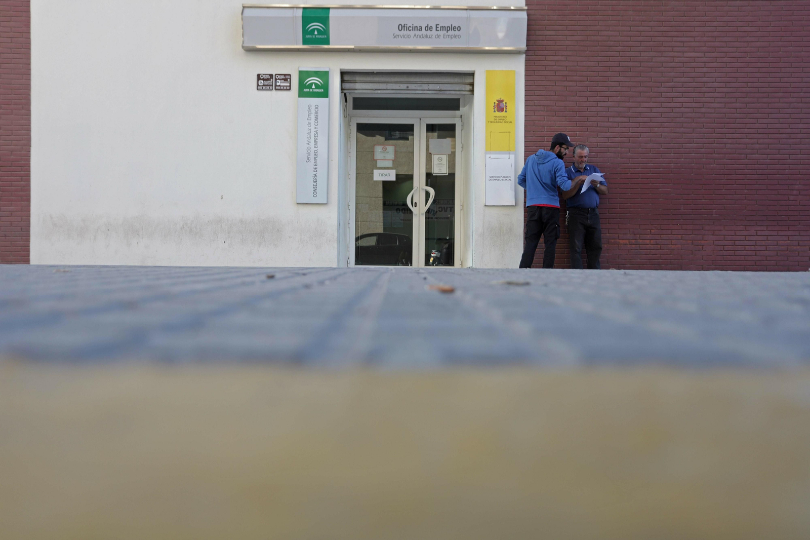 Dos personas conversan a las puertas de la oficina del SAE de Algeciras.