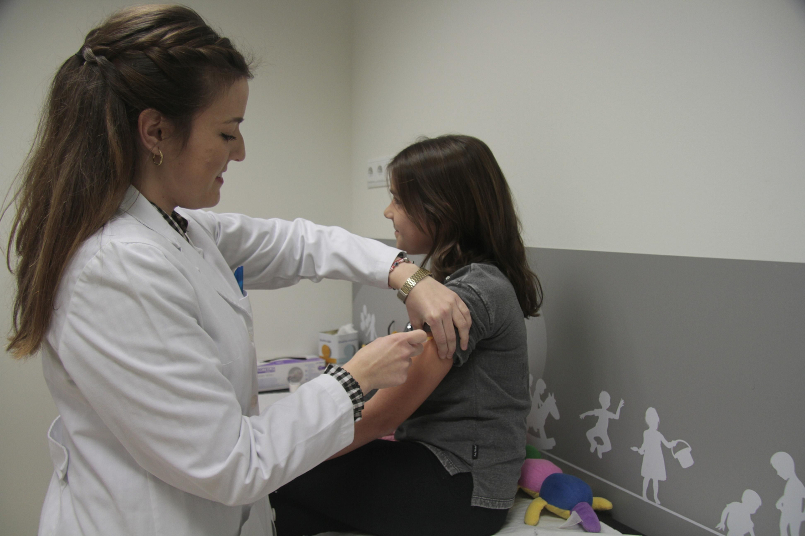 Una enfermera vacuna a una niña en una consulta.