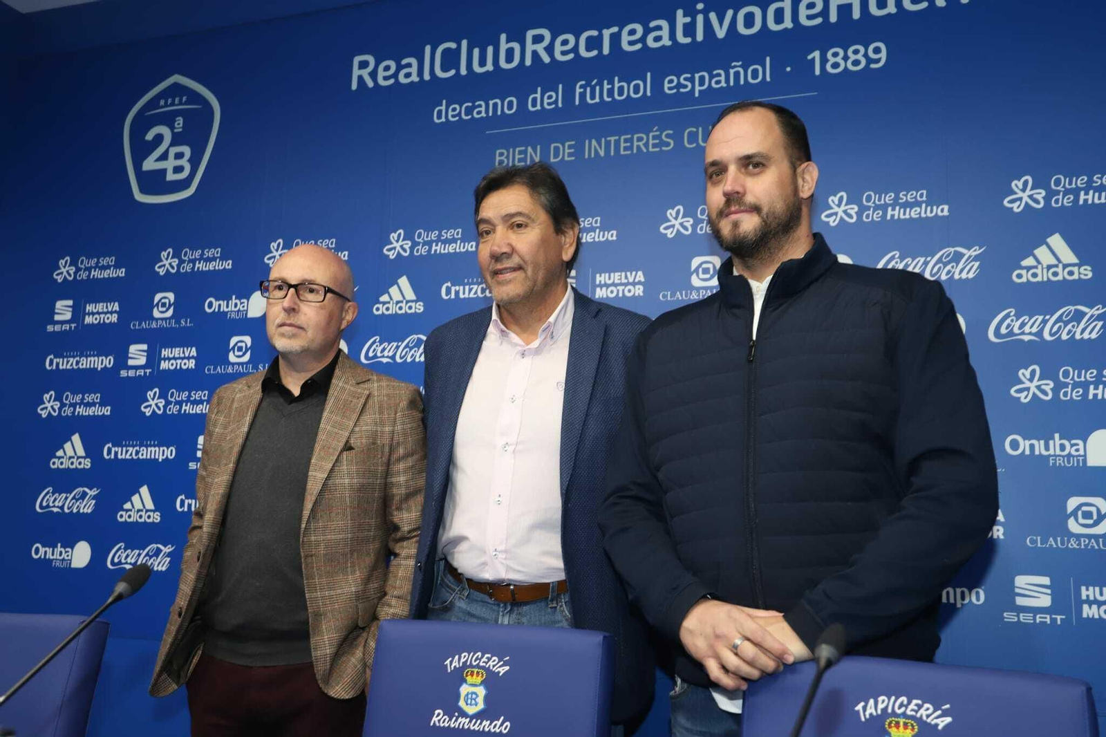 El presidente del Recreativo, Manolo Zambrano, junto a los representantes de Ilussia Sports, en la sala de prensa del Nuevo Colombino.