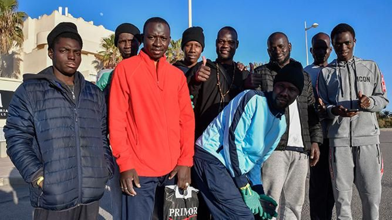 Un grupo de migrantes posa en la entrada de uno de los hoteles en El Toyo donde están alojados