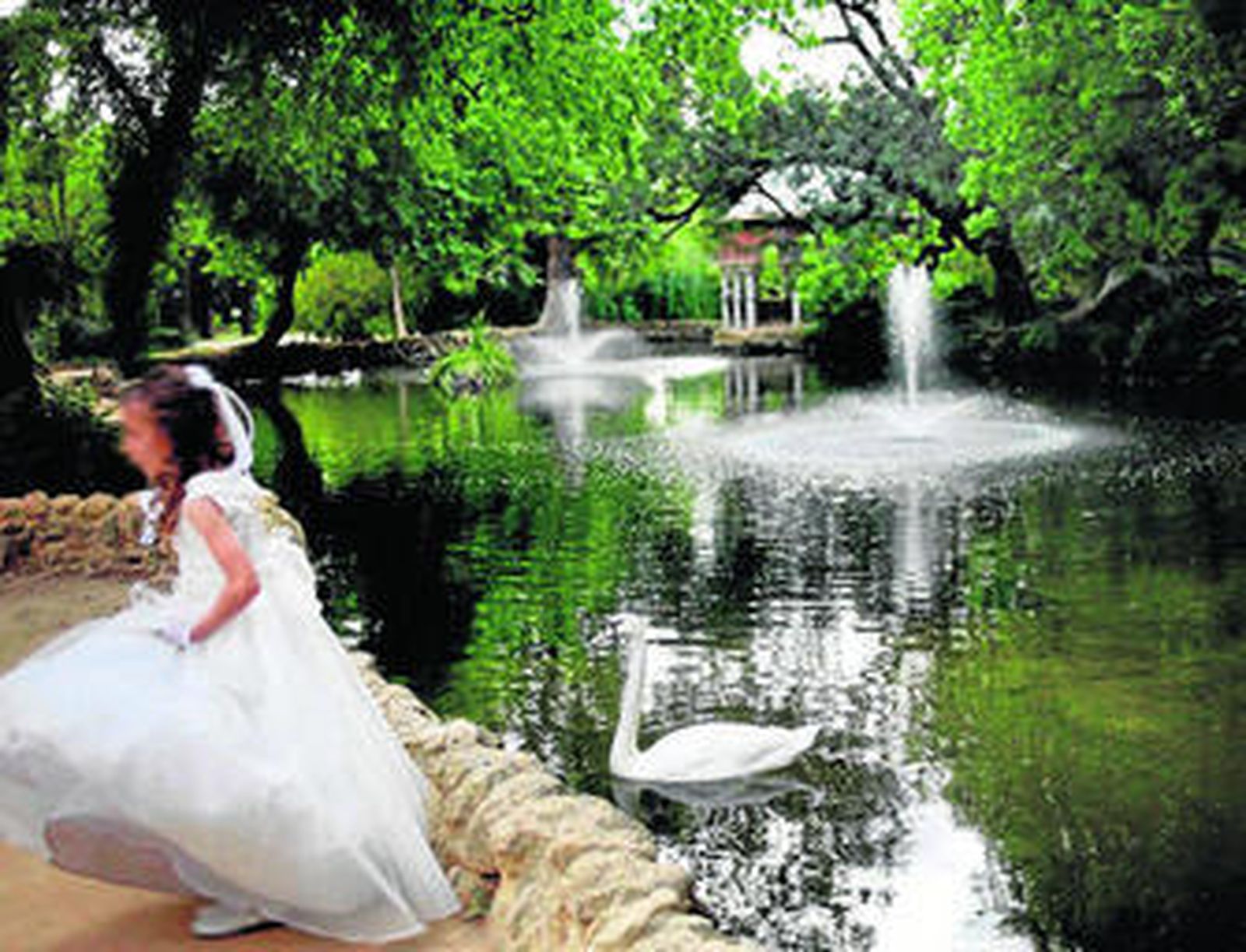 Una niña vestida de primera comunión se fotografía junto a la Glorieta de las Aves.