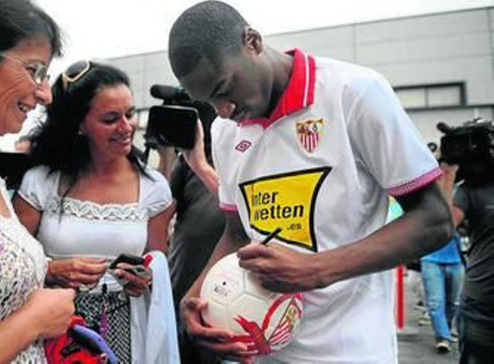 Kondogbia les firma un balón a dos aficionadas.