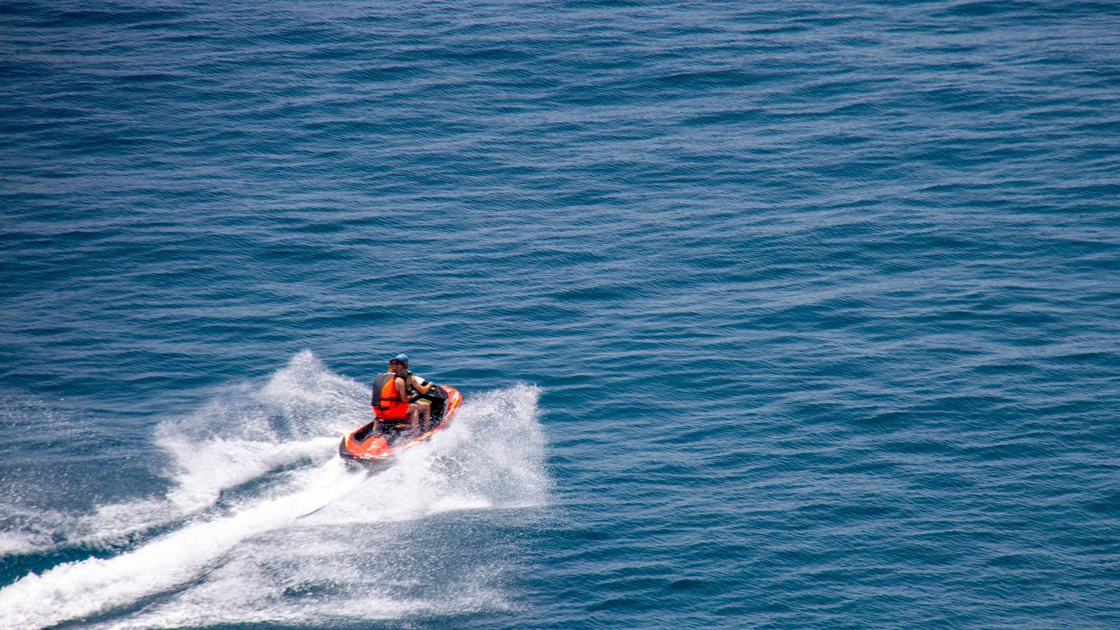 Dos personas en una moto acuática frente a Torrenueva Costa