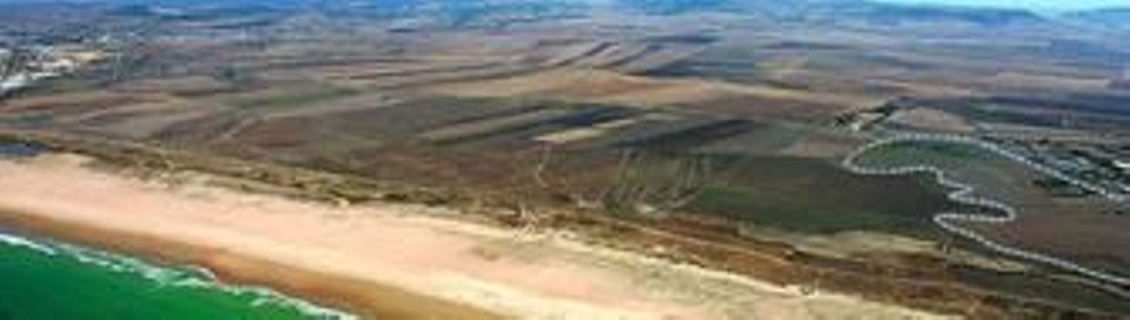 Panorámica del tramo de costa que une Conil y El Palmar, en el término municipal de Vejer. A la izquierda, la playa de Castilnovo, y a la derecha, marcada, la parcela hotelera de Malcucaña.