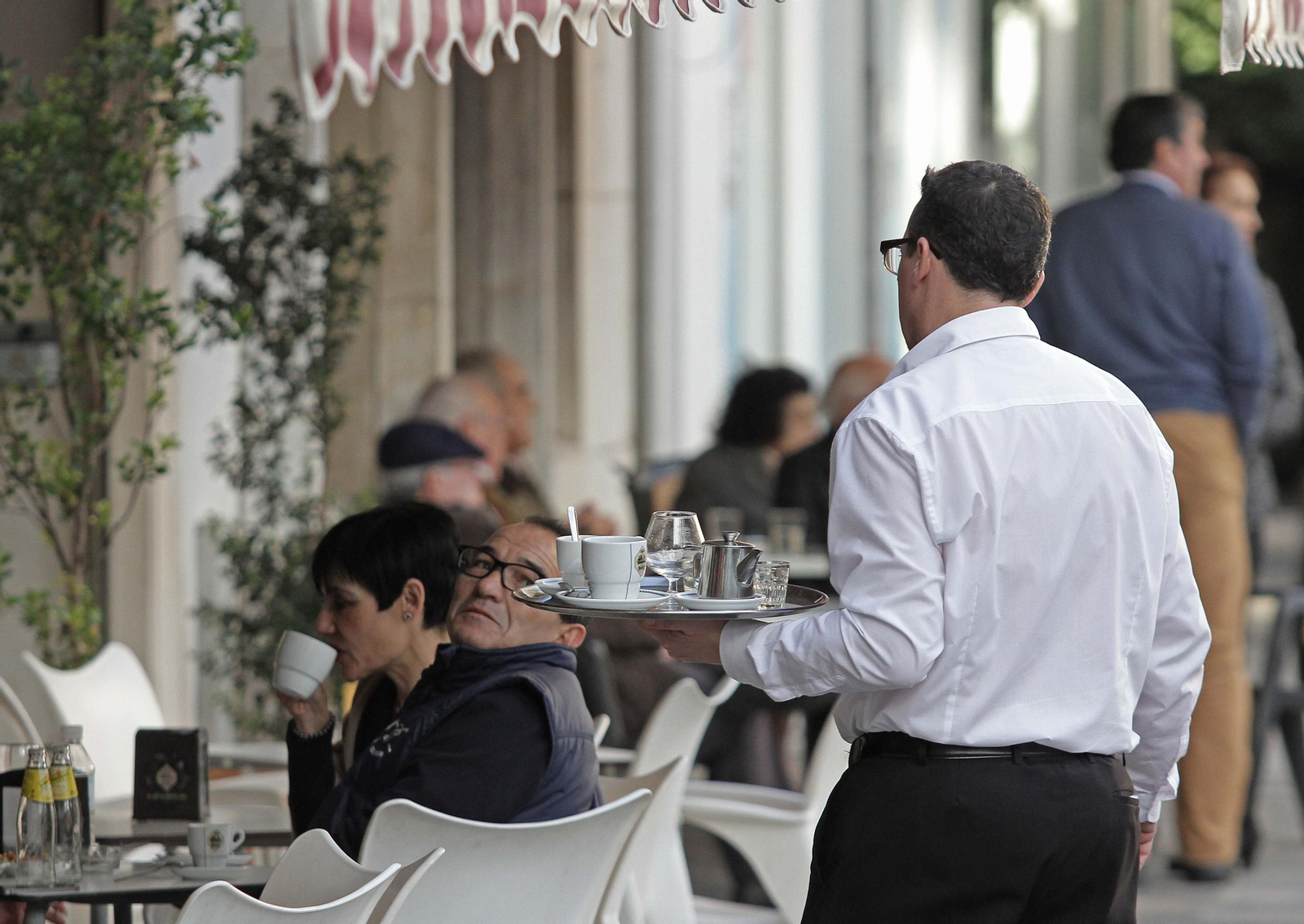Un camarero atiende una terraza.