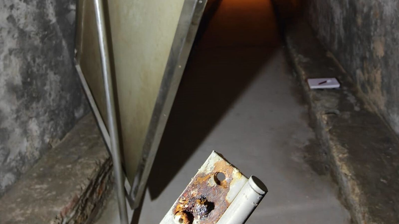 Cartel móvil desprendido y su bisagra oxidada