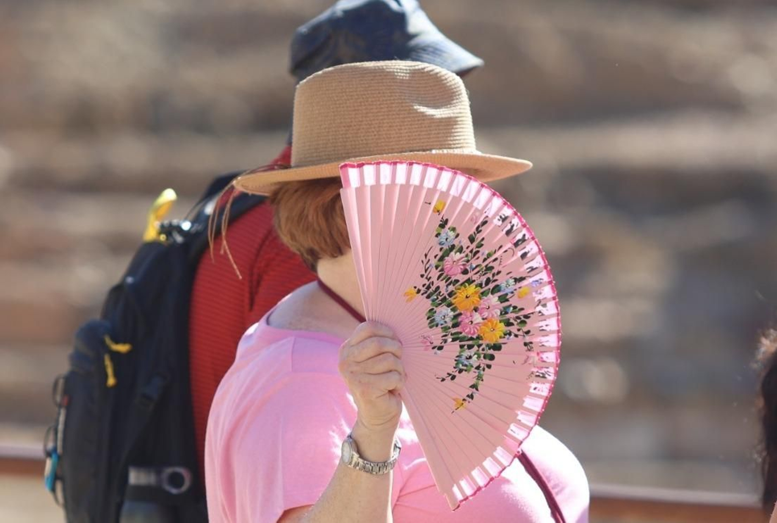 Una mujer se protege del sol con un abanico
