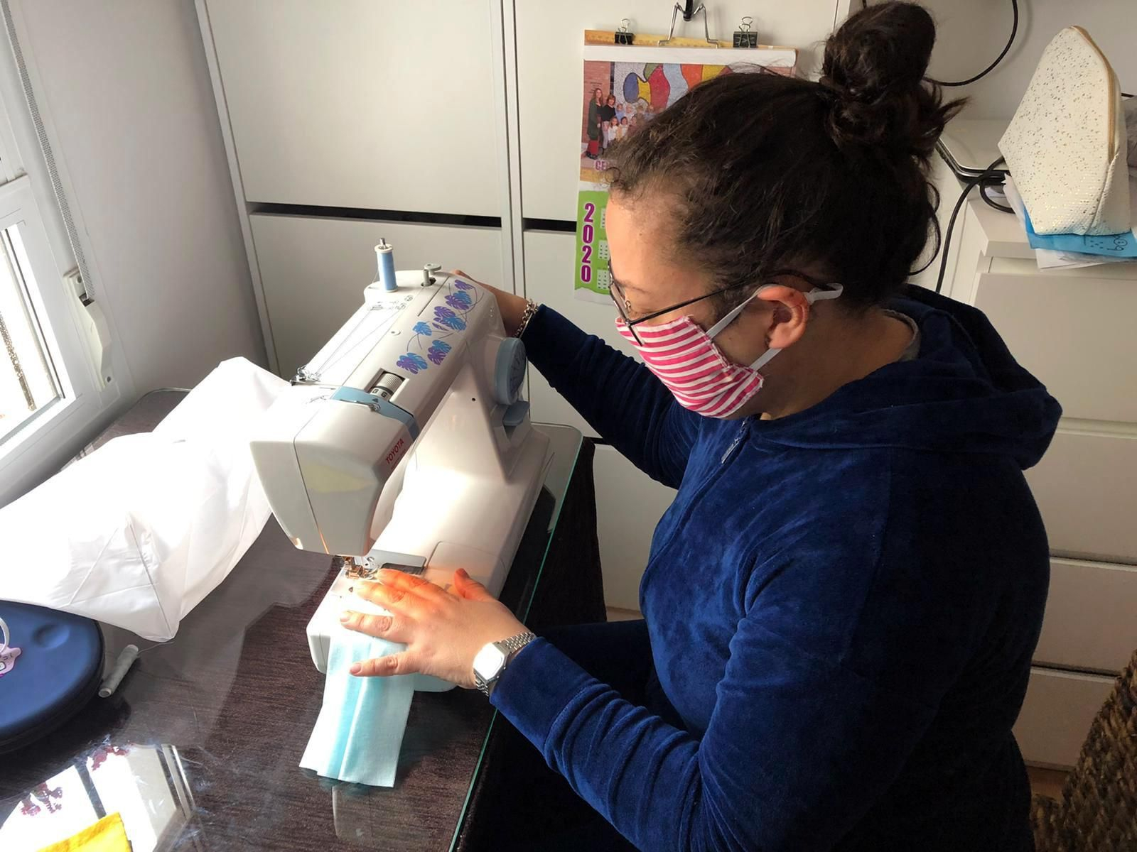 Una mujer cose una mascarilla.