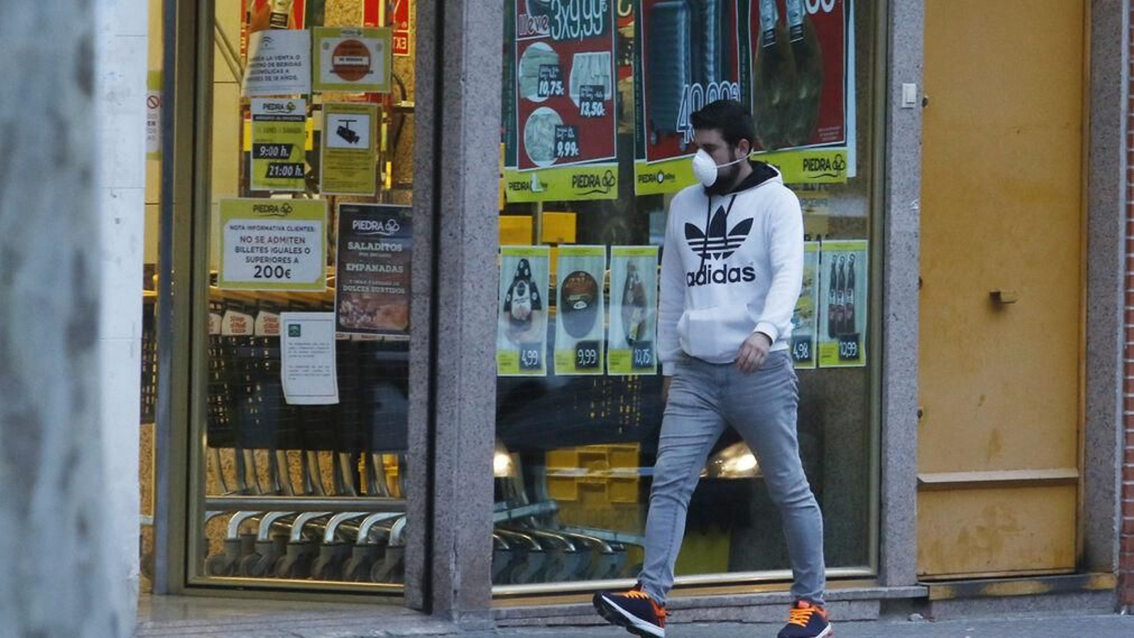 Un joven pasa delante de un supermercado, de los pocos establecimientos que están abiertos.