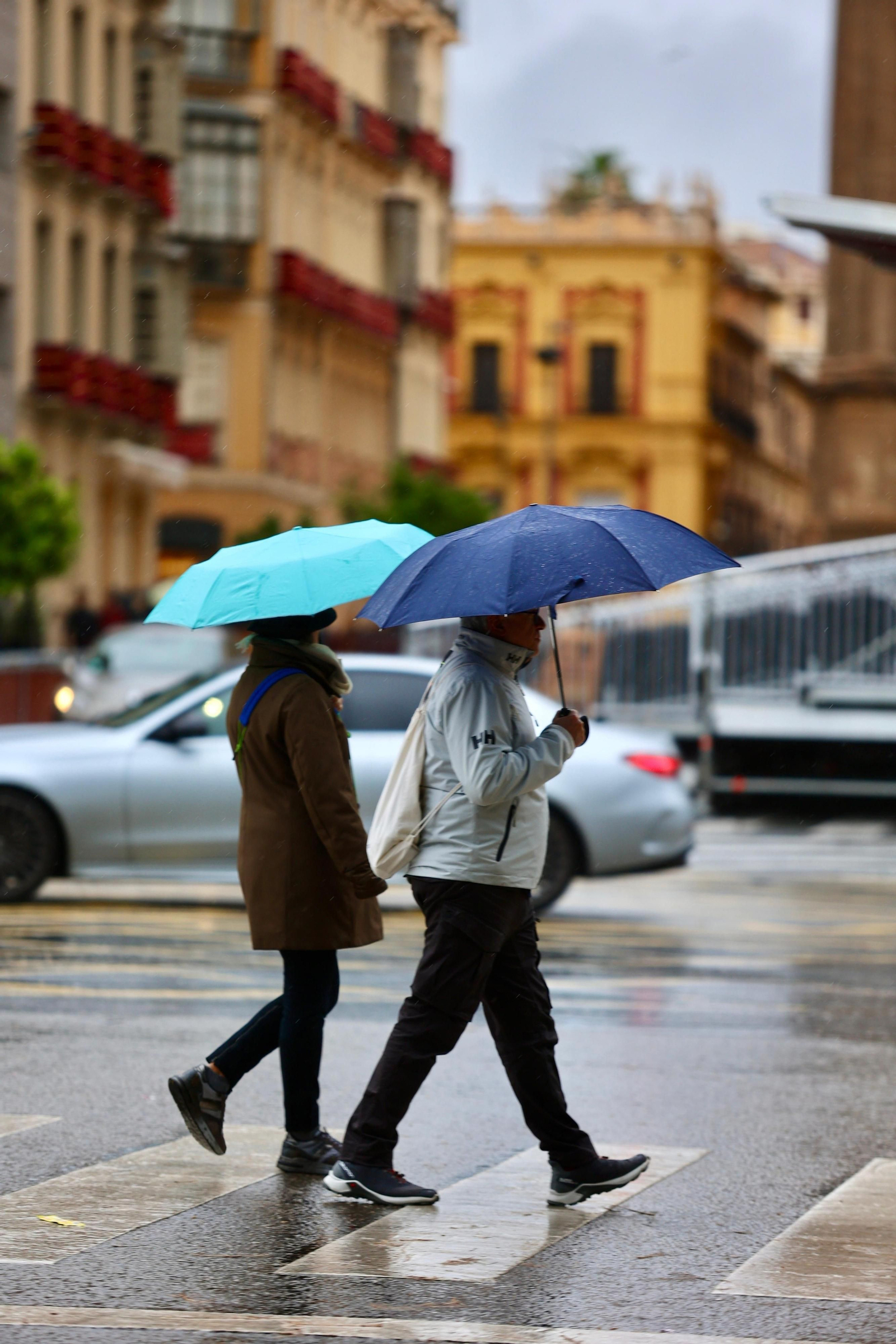 Dos personas se protegen de la lluvia en el centro, este sábado. Dos personas se protegen de la lluvia en el centro, este sábado.