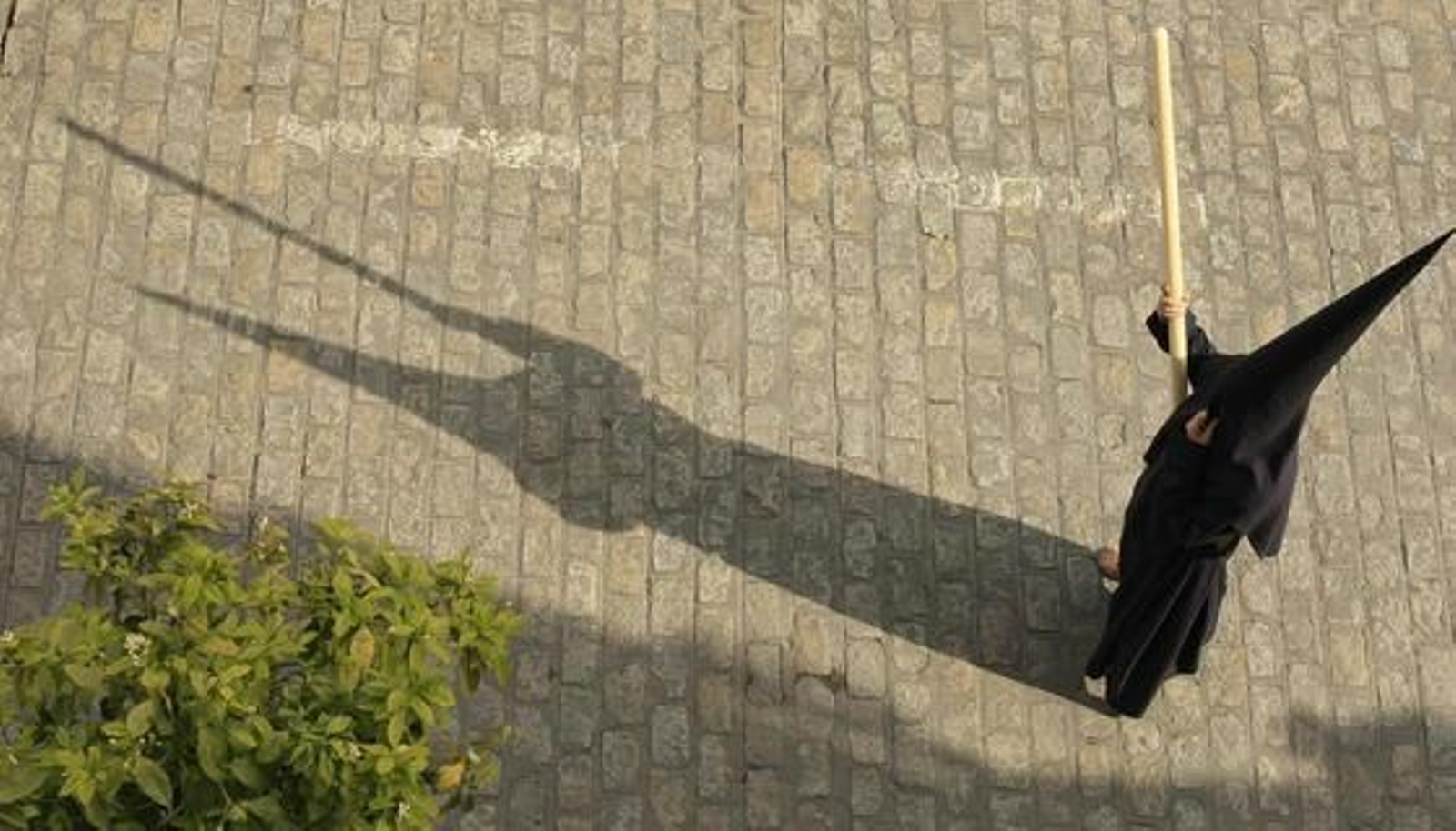 El sol de la tarde proyecta la sombra de un hermano del Santísimo Cristo del Perdón mientras hace estación de penitencia por el Arroyo.  Foto: Juan Carlos Toro