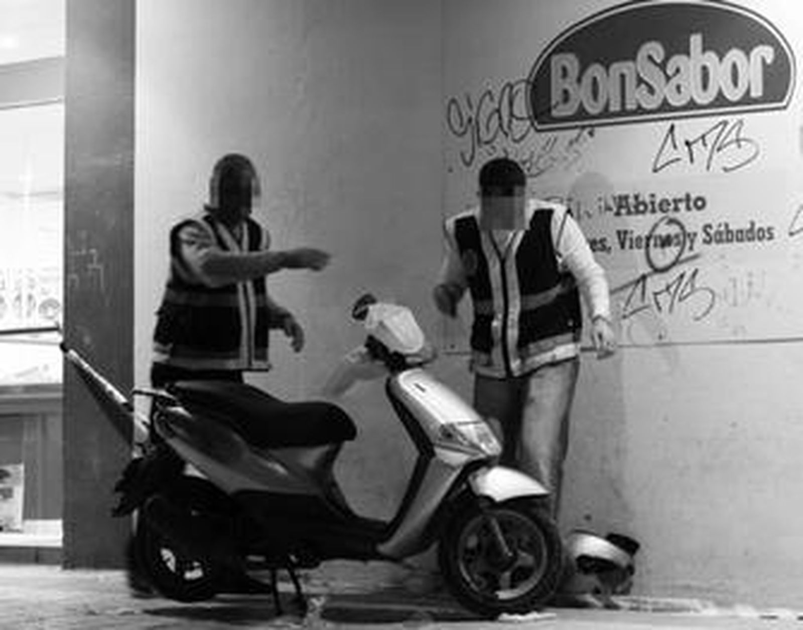 Dos policías examinan el vehículo de los atracadores del supermercado Bonsabor.