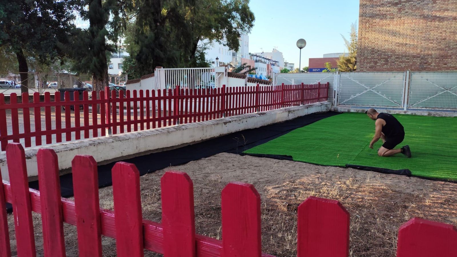 Uno de los padres colocando el césped artificial en el CEIP El Retiro, de Jerez.