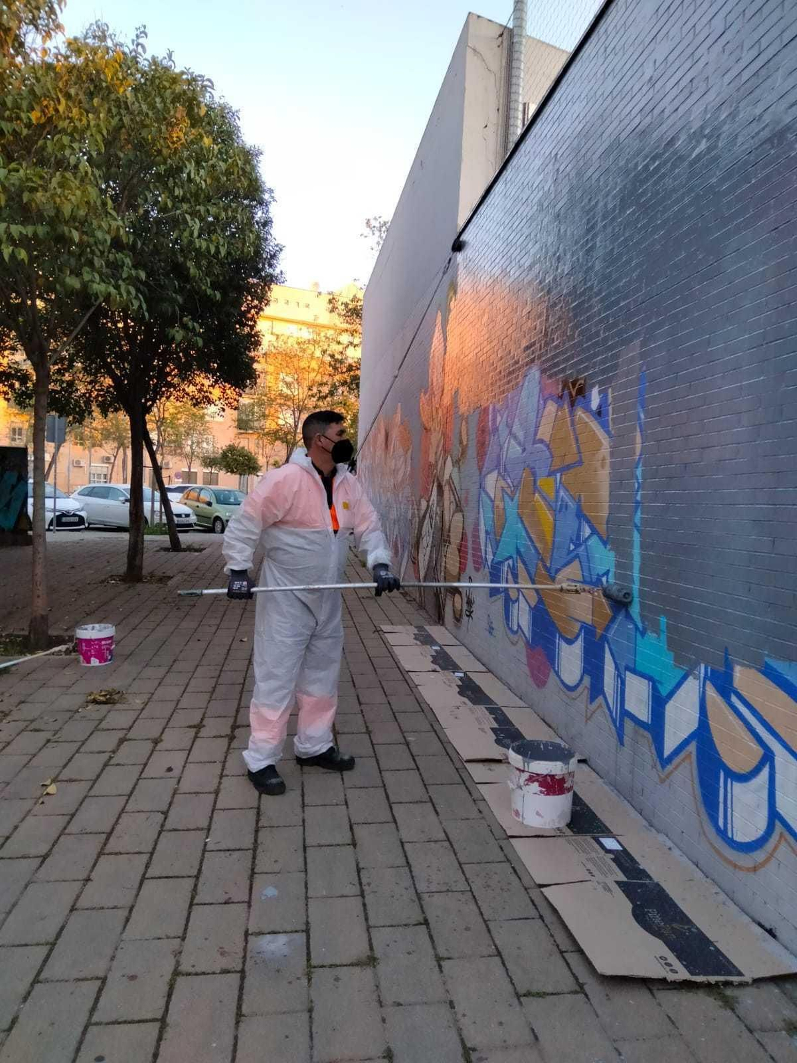 Un operario de la empresa de limpieza pinta una pared repleta de grafitis.