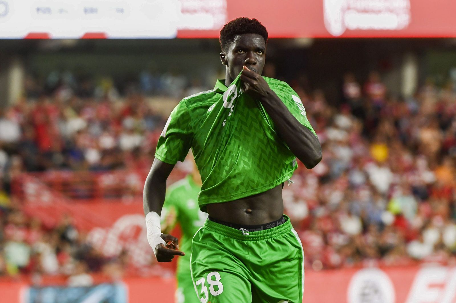 Assane Diao celebra su gol al Granada besándose el escudo del Betis en la camiseta.