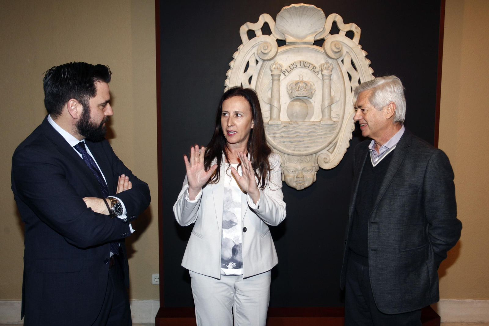 Remedios Palma habla con Fran González (izquierda) y Juan Alonso de la Sierra ante el escudo del siglo XVIII.