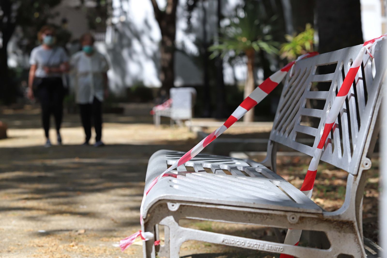 Un banco de un parque, con una cinta de prohibición de sentarse.